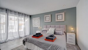 Une chambre à coucher moderne avec un grand lit, une table de chevet et une commode.