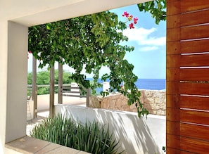 Ein Balkon mit Blick aufs Meer, einer Holz-Pergola und Grünpflanzen.