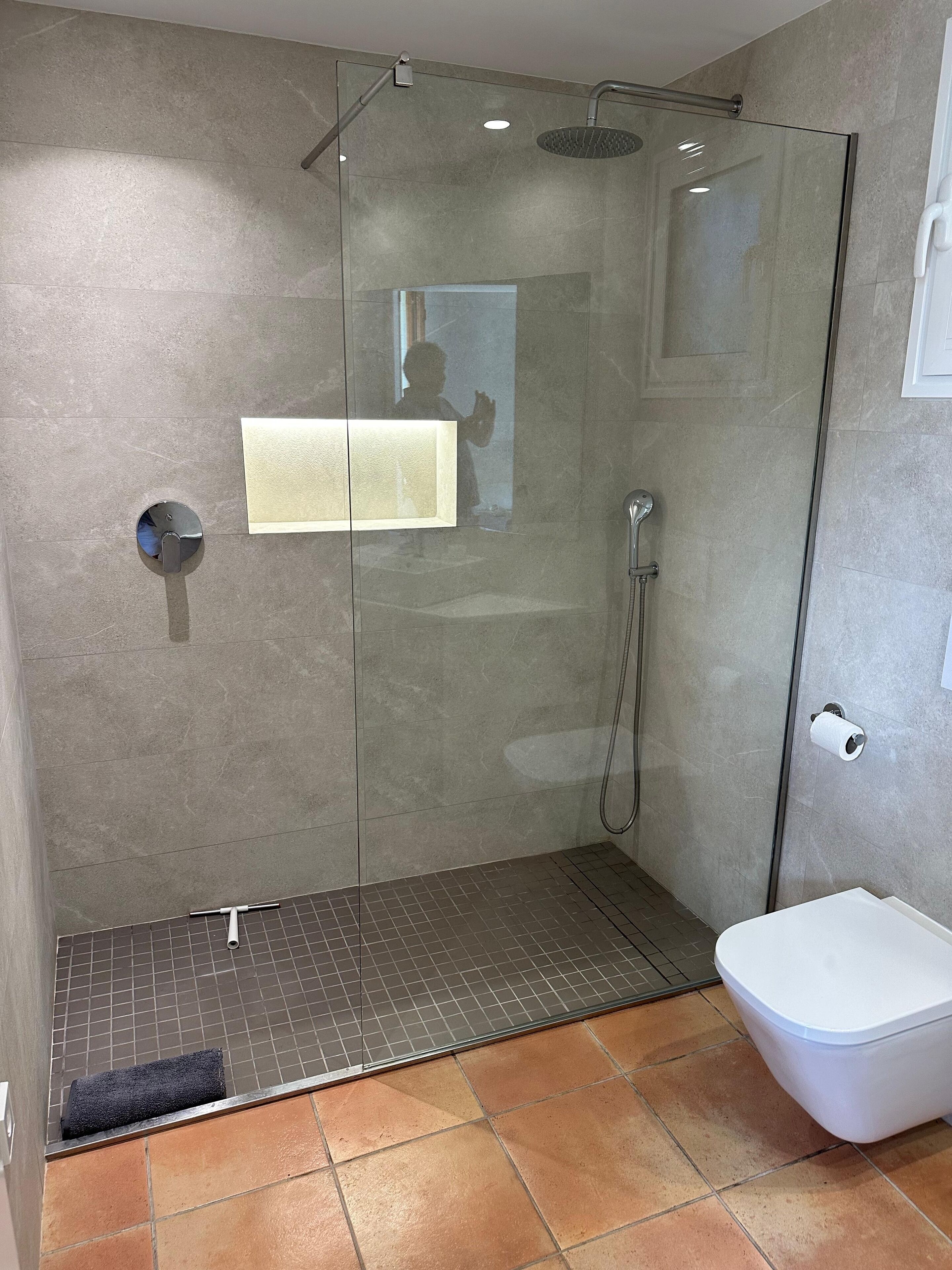 Un baño moderno con cabina de ducha de vidrio, inodoro y toallero.