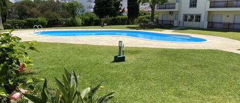 Ein Wohngebiet mit Schwimmbad, gepflegter Grünfläche und Wohngebäuden im Hintergrund.