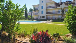 A multi-story hotel with a swimming pool, surrounded by well-maintained lawns and tropical plants. - Flat Bogart OCV - Oura Albufeira (Albufeira)