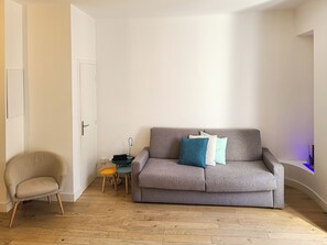 A living room with a grey sofa, a beige armchair, and a small side table with a lamp.