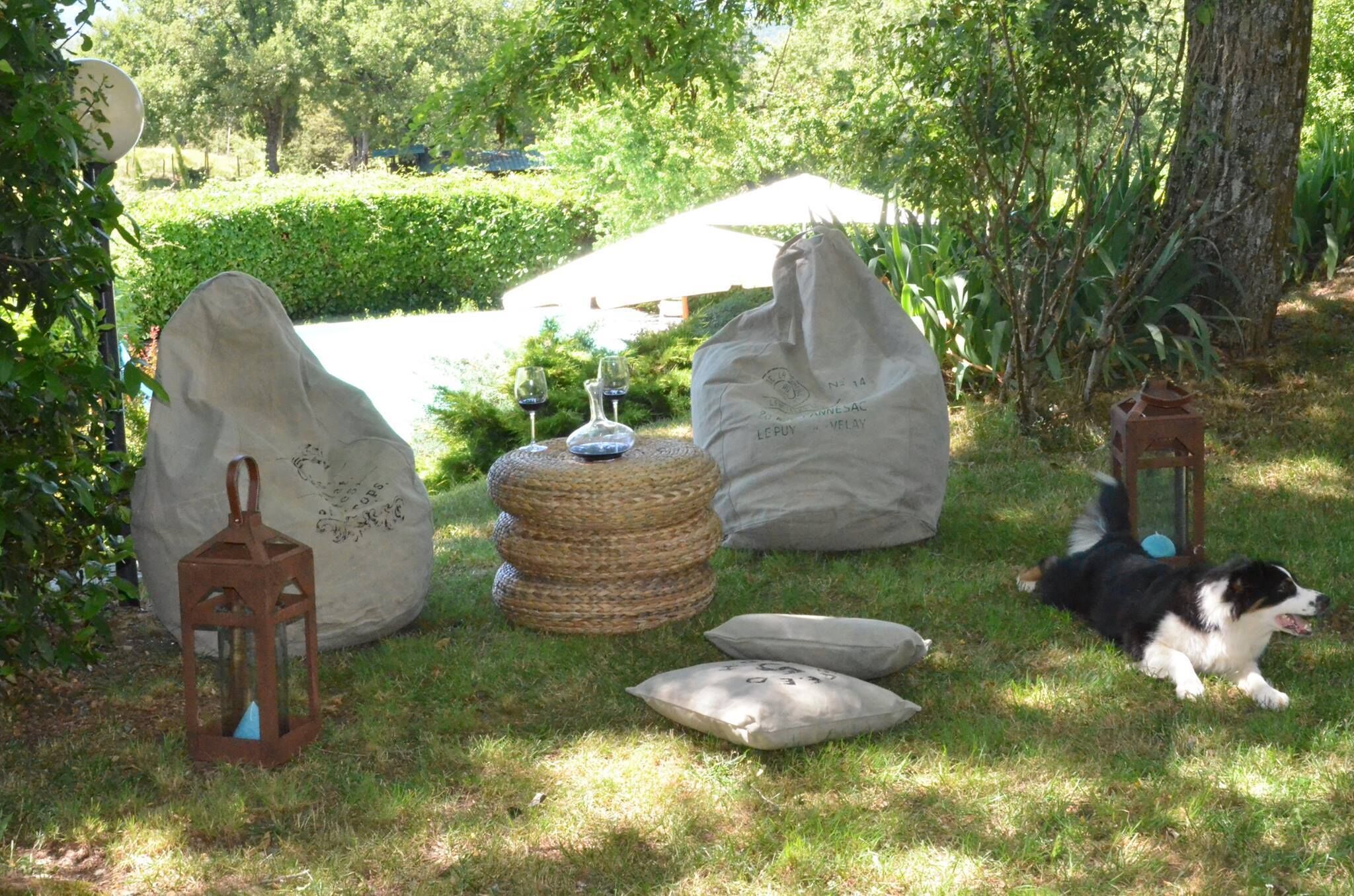 A garden setting with a stone lantern, a woven stool, and a dog.