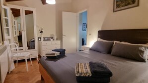 Un dormitorio con cama, cómoda, silla y espejo.