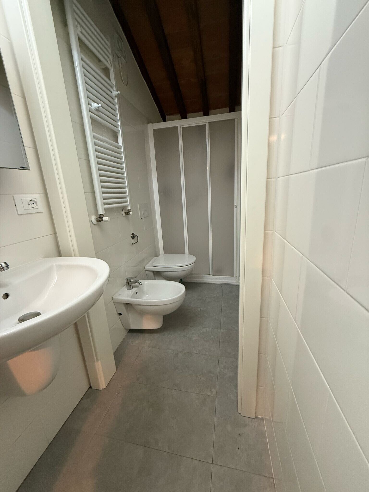 Un baño con lavamanos, dos inodoros y cabina de ducha.