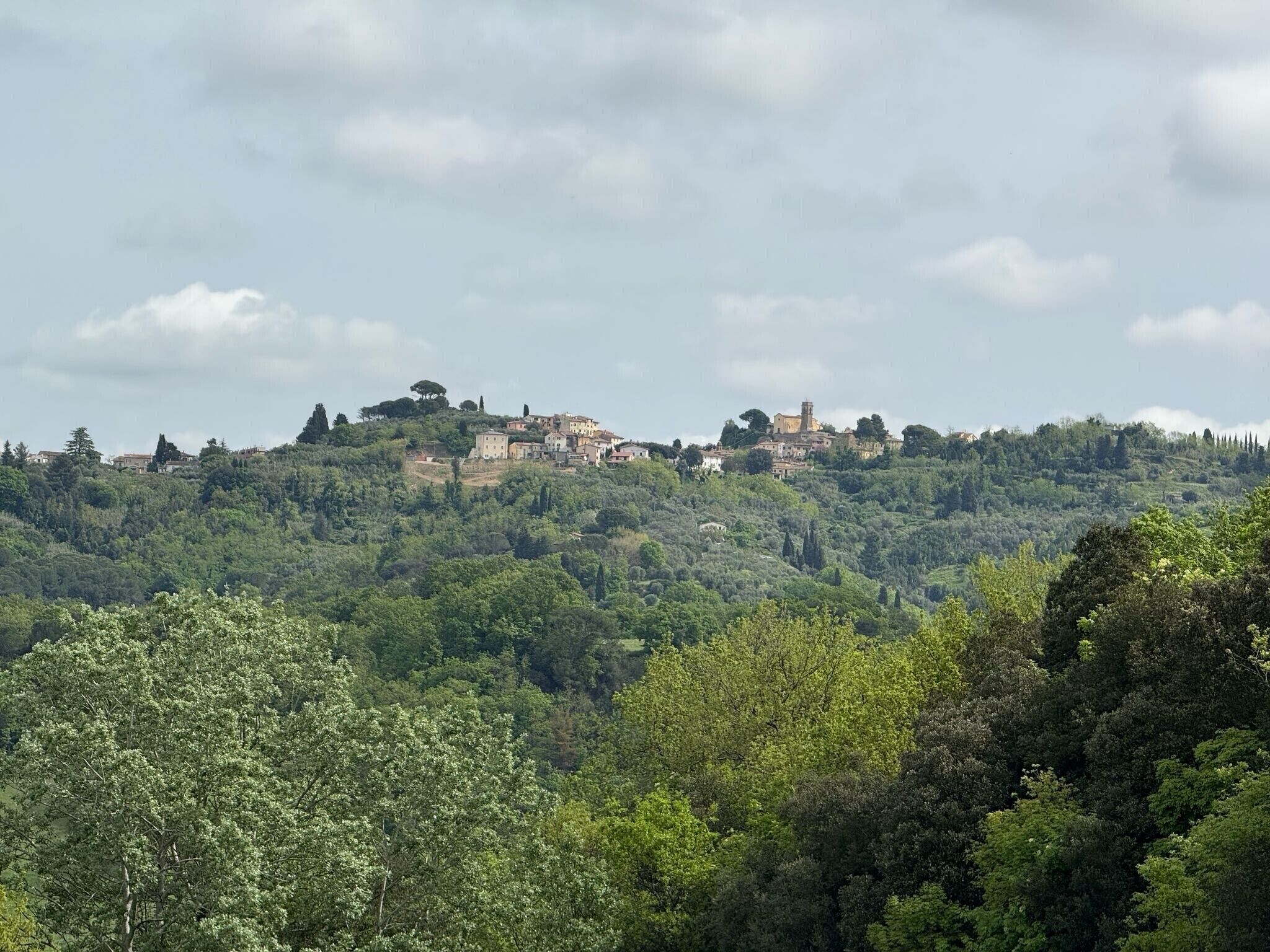 Un village perché sur une colline, avec des bâtiments nichés au milieu des arbres.