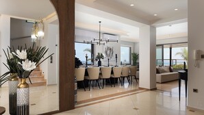A modern dining area with a large table, chairs, and a chandelier. There is a staircase in the background leading to an upper floor. - Villa Belle, Where Sea Views Meet Sunset Magic by etouri (Rethymno)