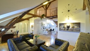 Un loft amplio con techo alto, vigas de madera a la vista, un comedor y una cocina.