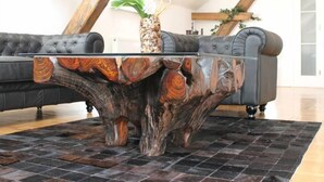 Una sala de estar moderna con una mesa de centro de madera única, un sofá de cuero negro y suelo de baldosas.