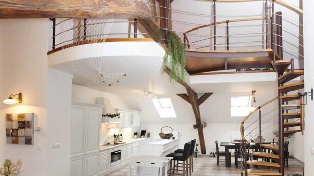 Un loft espacioso con techo alto, una escalera espiral de madera y una zona de cocina.