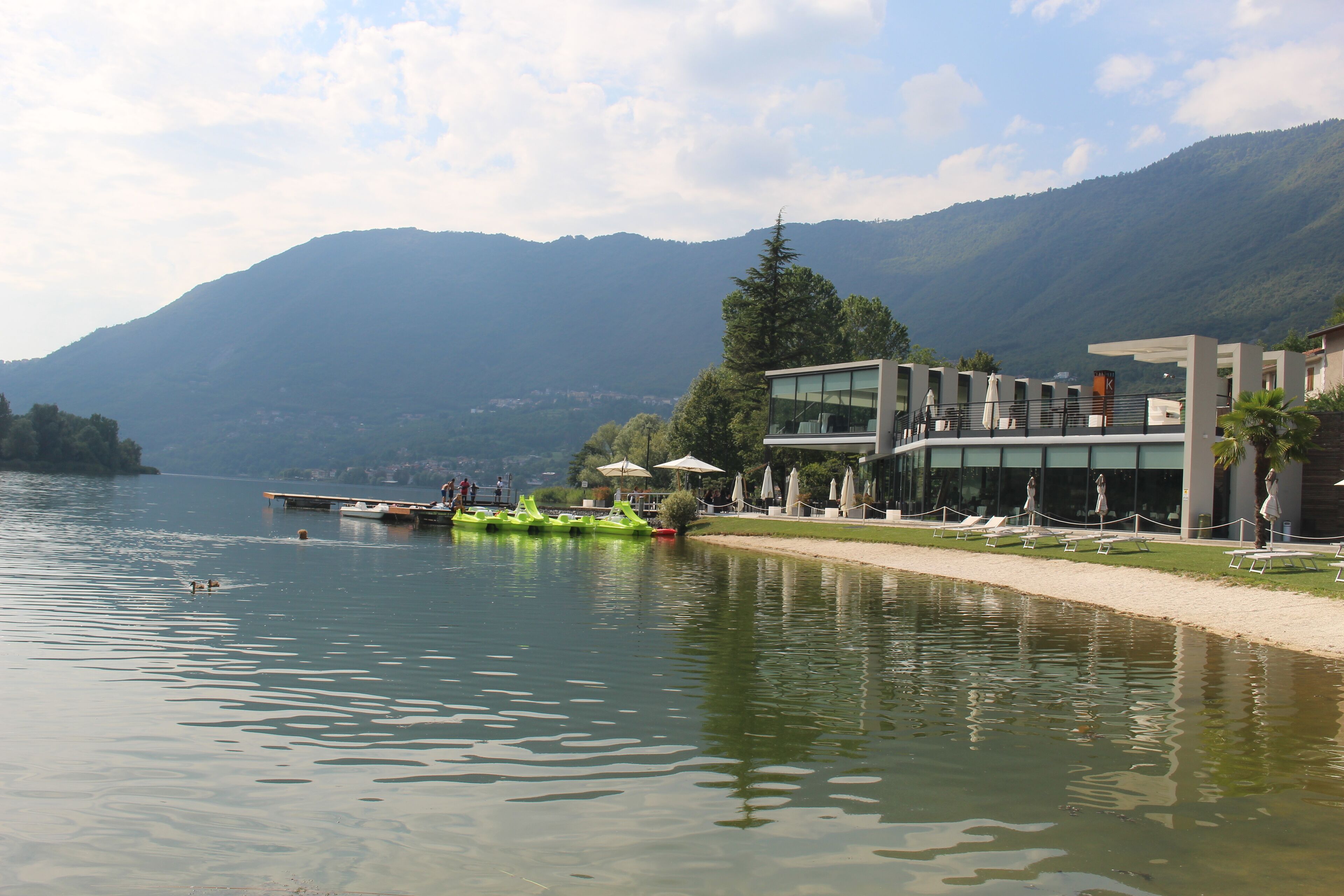 Un hotel frente al lago con comedor, zona de estar al aire libre y vistas a las montañas.