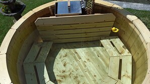 Een houten jacuzzi met een ingebouwde tafel en een gele badeend.