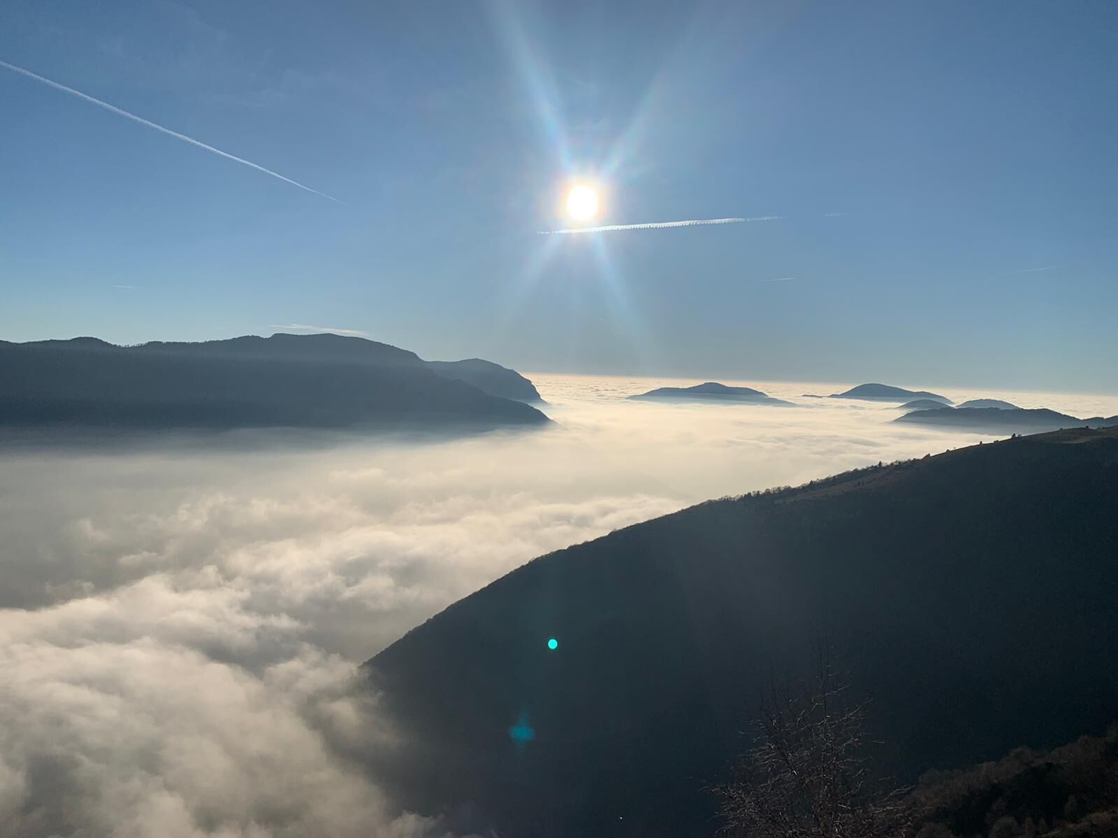 Paesaggio montano con cielo sereno e sole splendente.