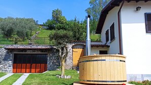 Een rustieke buitenruimte met een houten vat, een stenen muur en een houten deur.