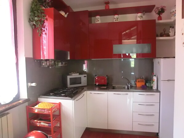 A compact kitchen with red cabinets, a microwave, a toaster, and a sink. - Villa with large garden and splendid sea view. Parking space and free Wi-Fi (Monterosso al mare)