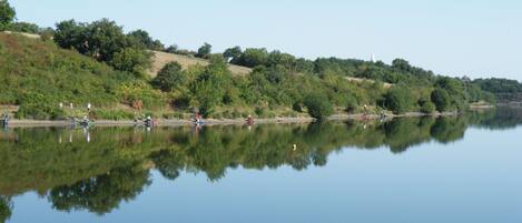 A calm lake with reflections of trees and people.