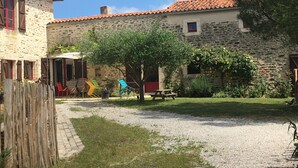 Un patio con un edificio de piedra, una valla de madera y una mesa de picnic.