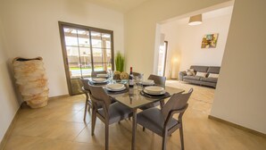 Un coin repas avec une table en verre, des chaises et une bouteille de vin.