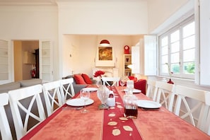 A dining area with a red tablecloth, white chairs, and a fireplace.