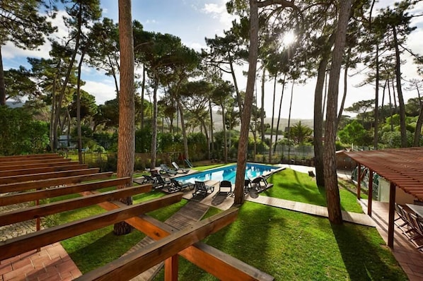 A pool area with lounge chairs and a wooden pergola.