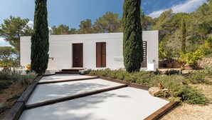A modern house with a white exterior, two wooden doors, and a paved pathway leading to the entrance. - New and modern House with pool in San Jose, 2 people (IBIZA)