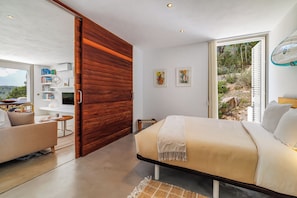 Relax in this serene bedroom with a large bed, a cozy seating area, and a scenic view.
