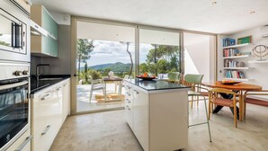 A modern kitchen with a large island, a dining area with a view, and a bookshelf. - New and modern House with pool in San Jose, 2 people (IBIZA)