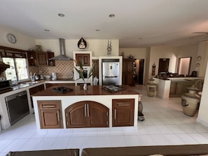 A spacious kitchen with a central island, wooden cabinets, and a stainless steel refrigerator.