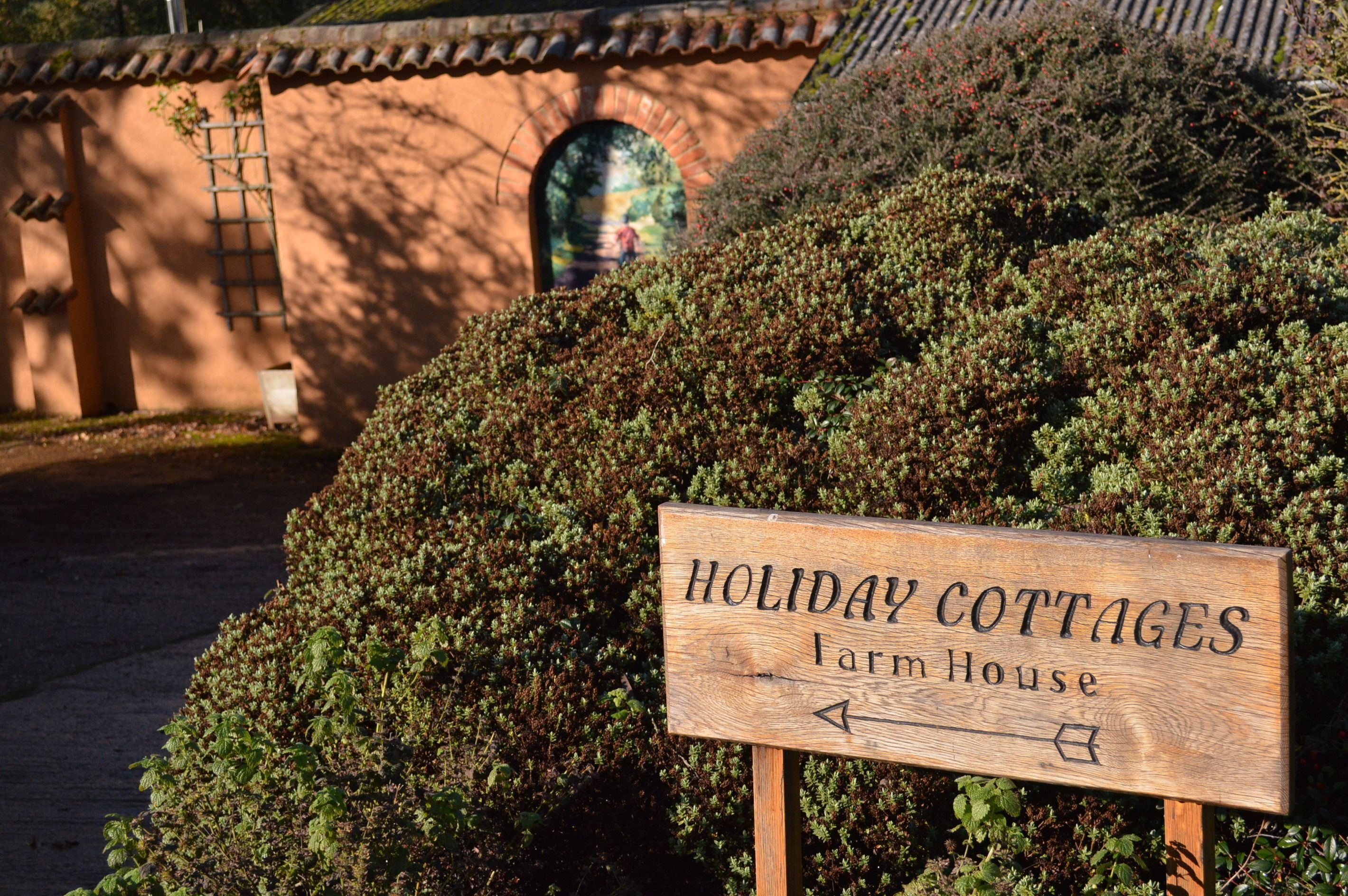 A wooden sign for 'Holiday Cottages Farm House' with directional arrows.