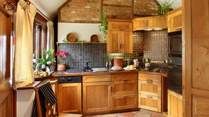 A kitchen with wooden cabinets, a tiled backsplash, and a brick ceiling. - The cosiest and quaintest haven for couples, near Great Tew (Chipping Norton)