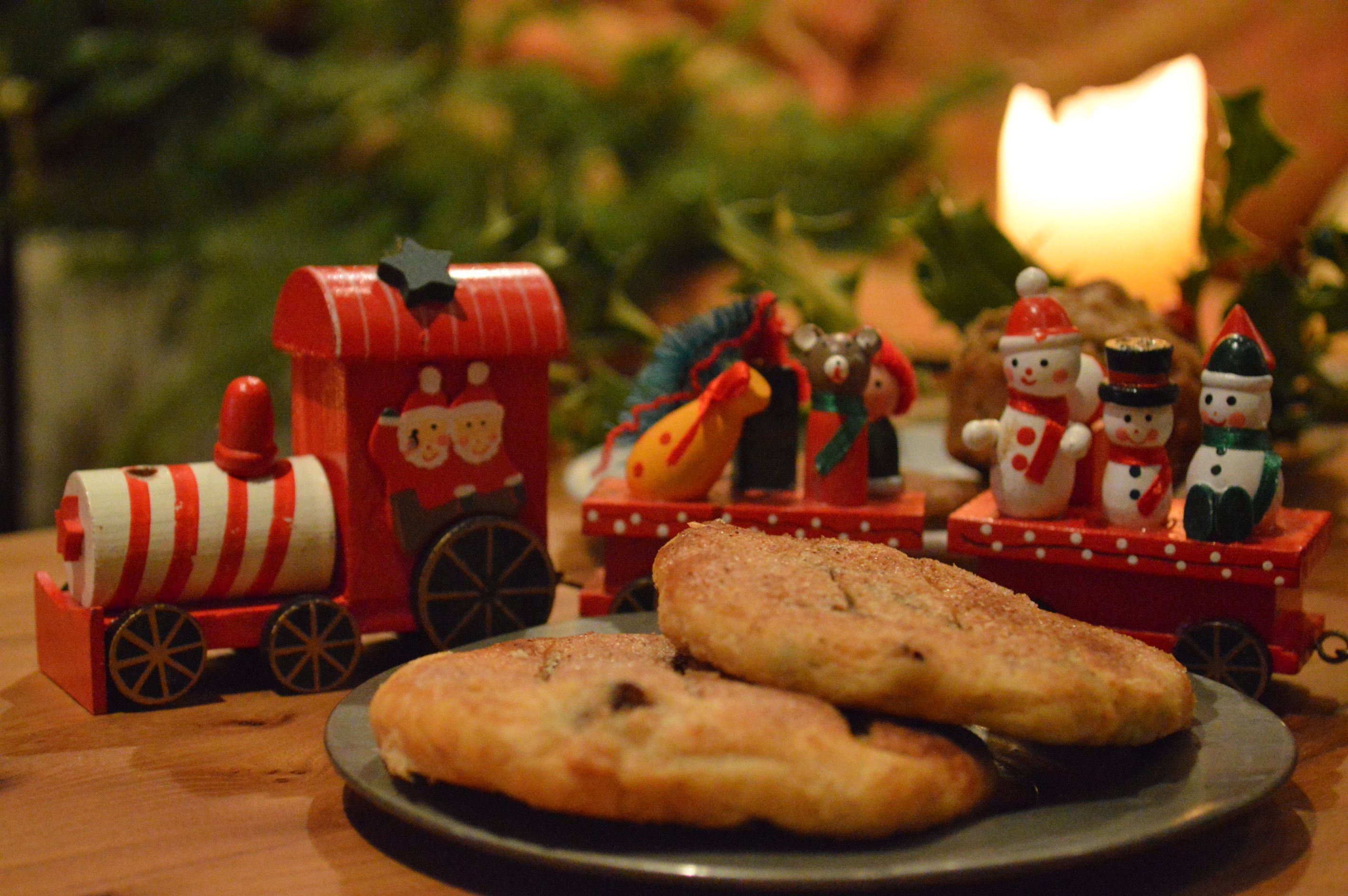 A plate with two cookies and a small red train with snowmen and a character on it.