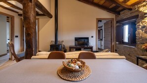 Une pièce chaleureuse avec une cheminée, un téléviseur et une table à manger agrémentée d’un set de table en fibres tressées.