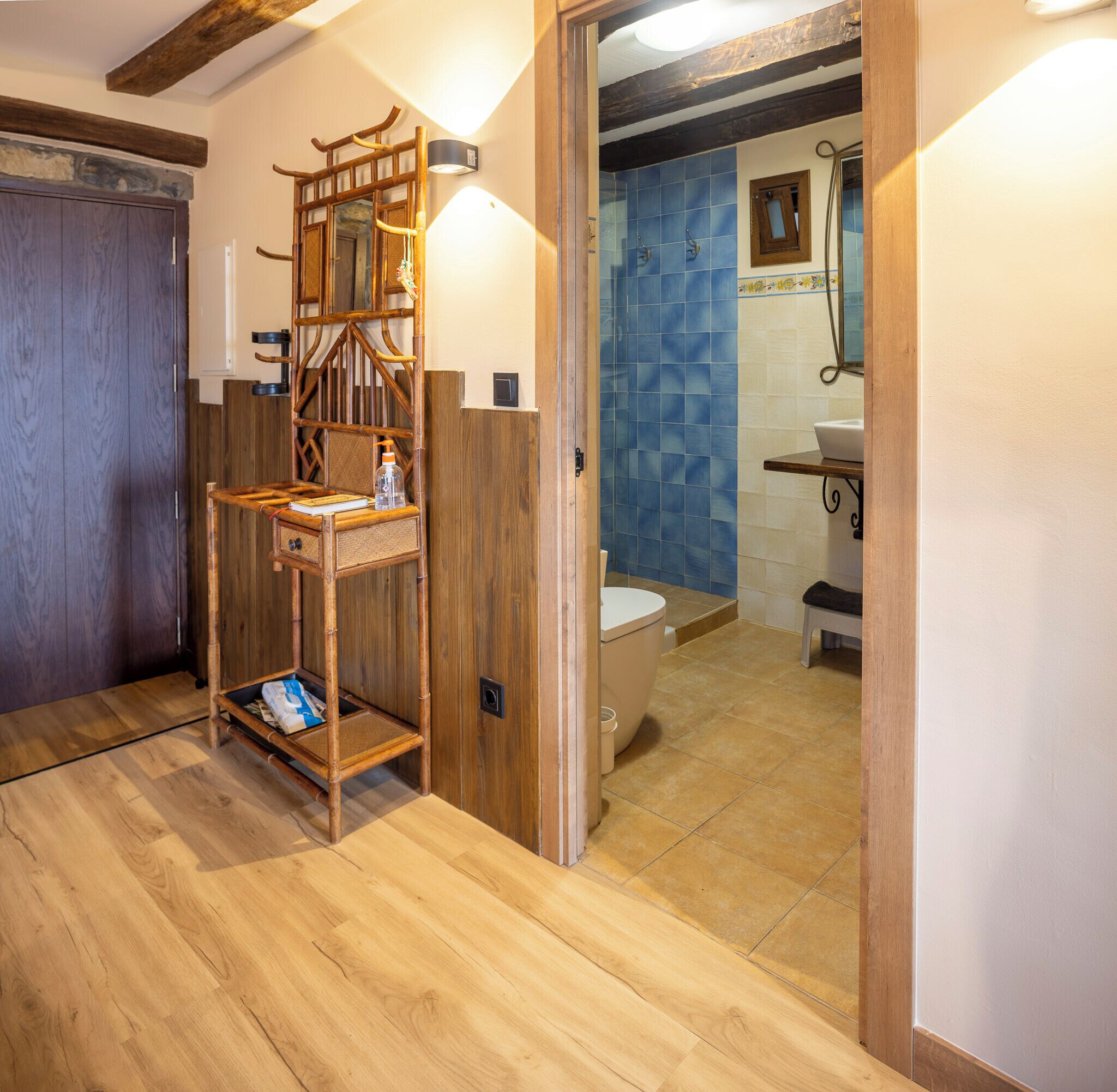 Ein Badezimmer mit Holzrahmen, das eine Toilette, ein Waschbecken und ein Ablagefach mit Pflegeprodukten beinhaltet.