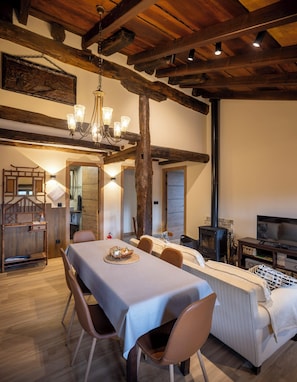 A dining area with a table set for four, a sofa, a television, and a fireplace. - This rural apartment has 65m2, 3 bedrooms and 2 bathrooms, in addition to the kitchen-living room. (Aia)