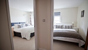 A hotel room with two beds, a wooden floor, and a white wall. - Toothbrush Apartments - Central Ipswich - St Peters St (Ipswich)