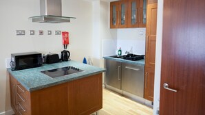 A modern kitchen with a stainless steel range hood, a built-in microwave, a toaster, and a sink. - Toothbrush Apartments - Central Ipswich - St Peters St (Ipswich)