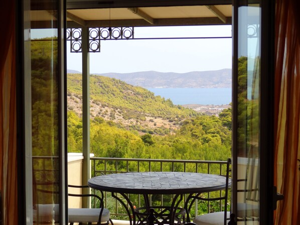 A balcony with a table and chairs, overlooking a mountainous landscape and a body of water. - Pepy's Villa - Private & luxurious, with Swimming pool, near several beaches (Lavrio)