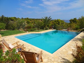 A rectangular swimming pool with stone tiles, surrounded by a well-maintained lawn and various plants. - Pepy's Villa - Private & luxurious, with Swimming pool, near several beaches (Lavrio)