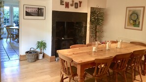 Ein Essbereich mit Holztisch und -stühlen, einem Kamin und einem Schild mit der Aufschrift 'ENJOY'.