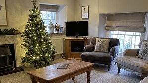 Ein gemütliches Wohnzimmer mit Kamin, Weihnachtsbaum, Flachbildfernseher und bequemen Sitzmöglichkeiten.