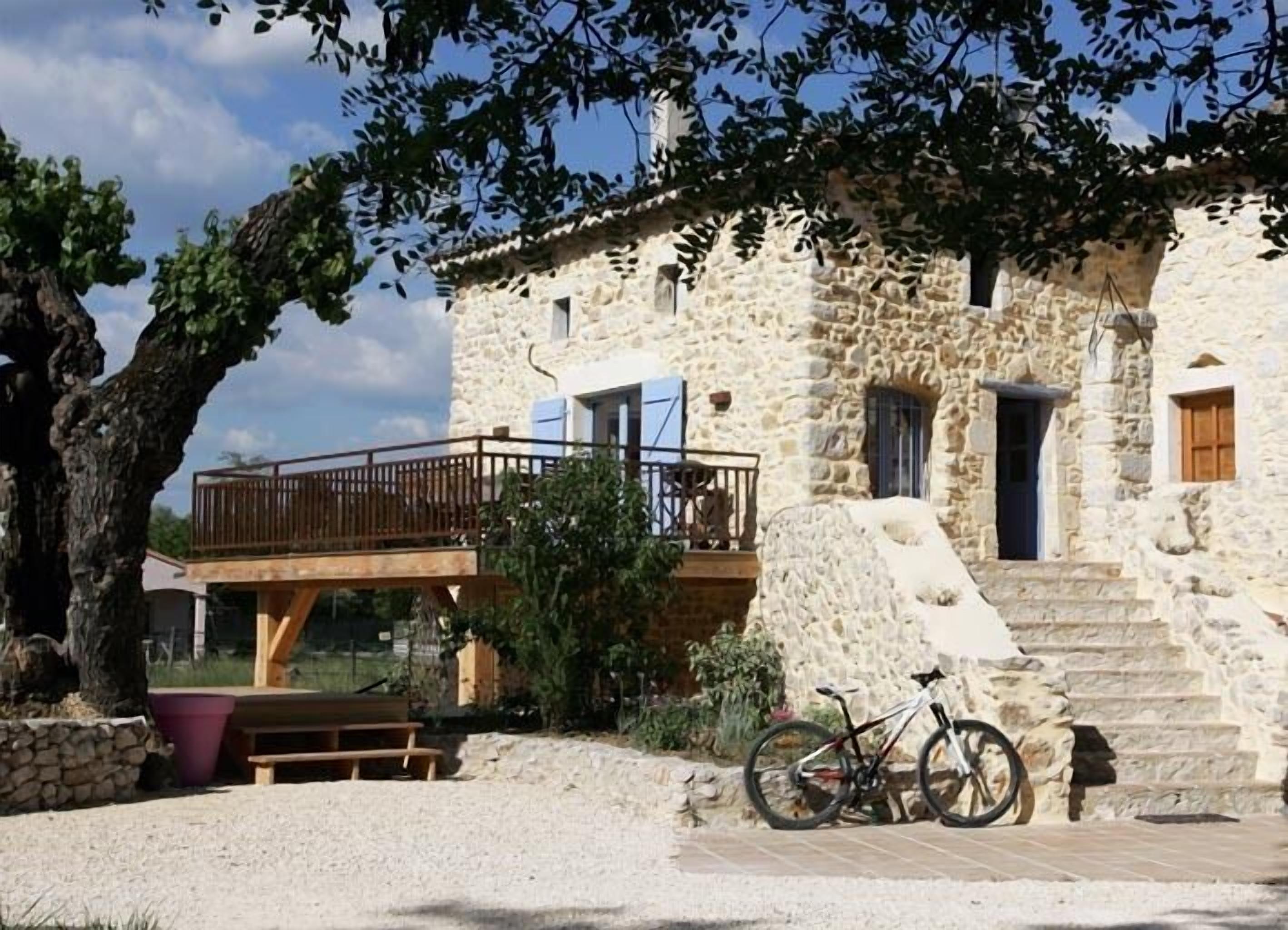 Un bâtiment en pierre doté d’un balcon en bois et d’un escalier menant à l’entrée.