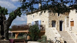 A stone building with a wooden balcony and a staircase leading to the entrance. - SUPERB AIR-CONDITIONED STONE GITE, HEATED SWIMMING POOL, NEAR THE VALLON CENTER (Vallon-Pont-D'arc)
