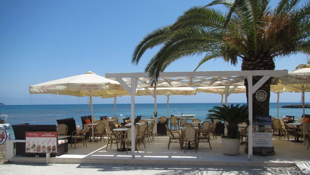 Un café junto a la playa con terraza y sombrillas, con vistas al mar.