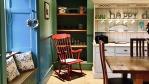 Une cuisine avec une porte bleue, un fauteuil à bascule et une table à manger.