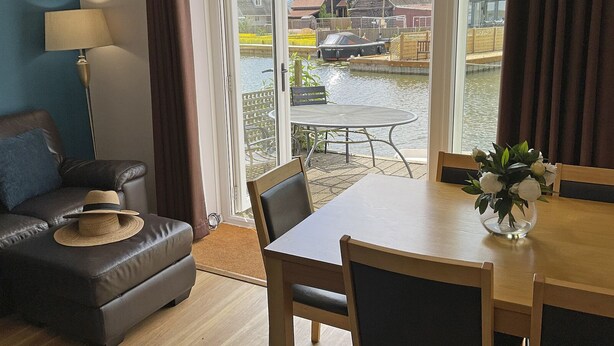 Ein Wohnzimmer mit einer Couch, einem Esstisch und Blick auf einen Kanal mit Booten.