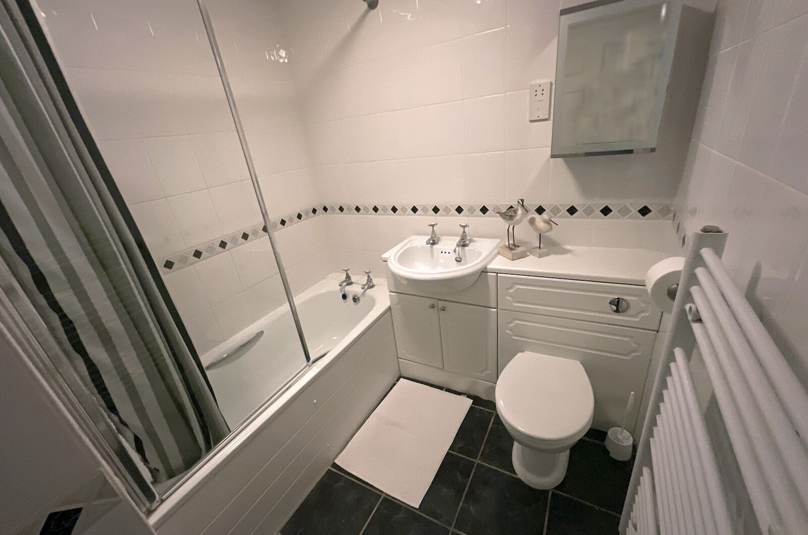 A bathroom with a glass shower enclosure, a white sink, a toilet, and a towel rack.