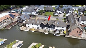 A riverside building with a dock, surrounded by residential houses. - 3 Bedroom Swan Cottage  In Wroxham, Norfolk, Norfolk Broads, England  (Wroxham)