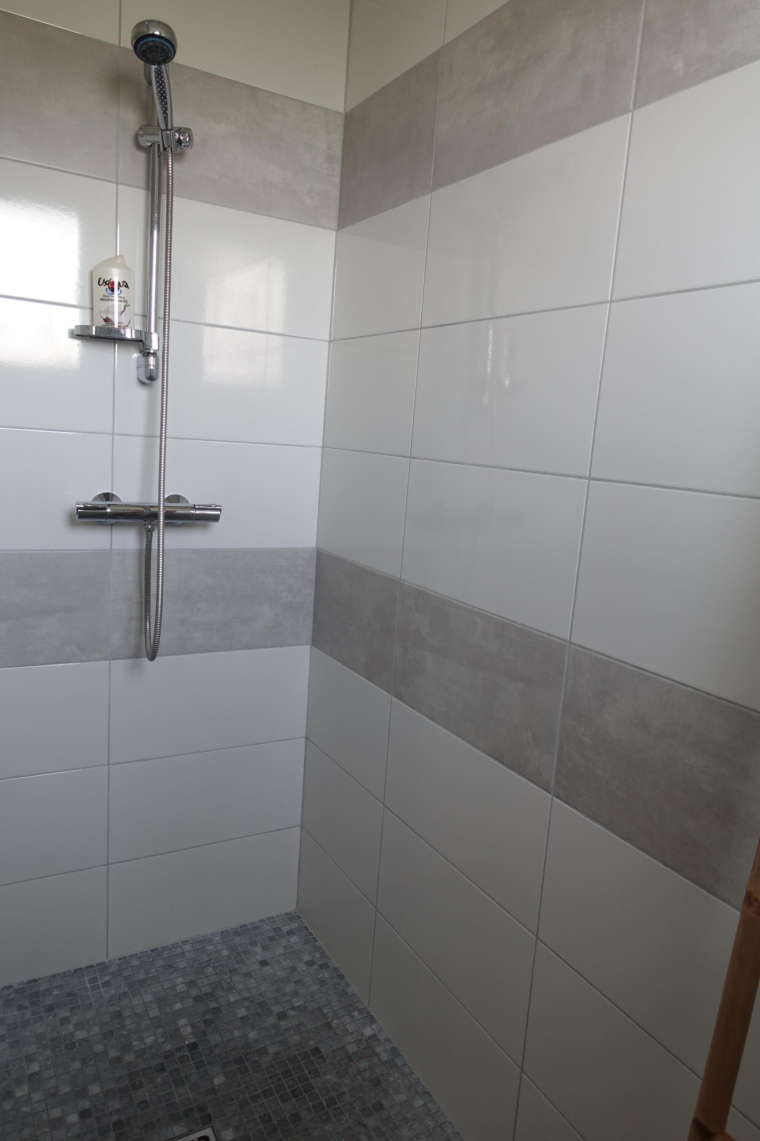 Zona de ducha con cabezal de ducha de mano y grifo empotrado.
