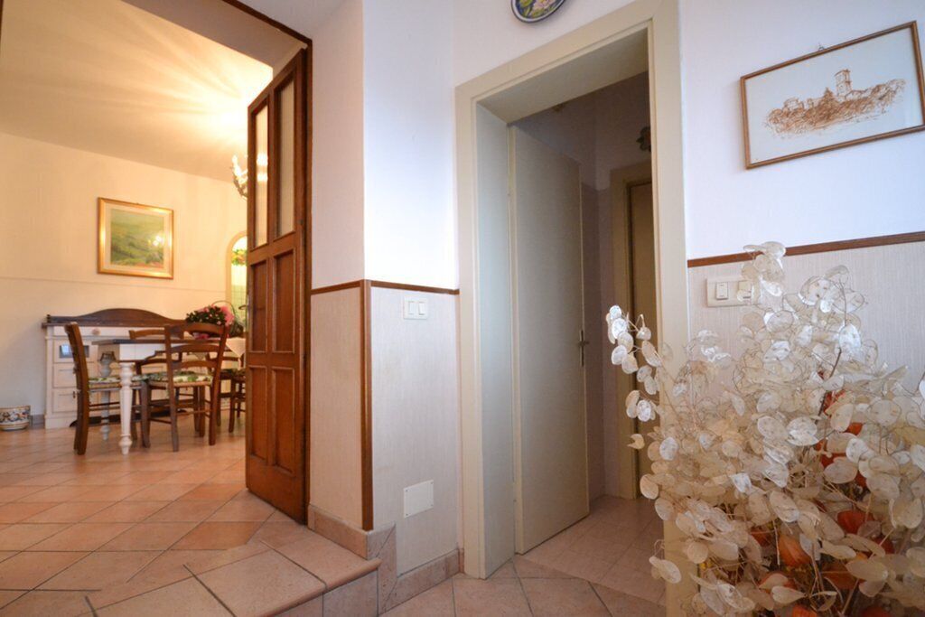 Una habitación con una mesa de comedor y sillas, una puerta de madera y una pared blanca con un cuadro enmarcado.