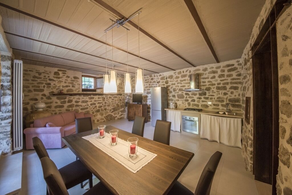 A spacious dining area with a wooden table, stone walls, and a cozy seating arrangement.